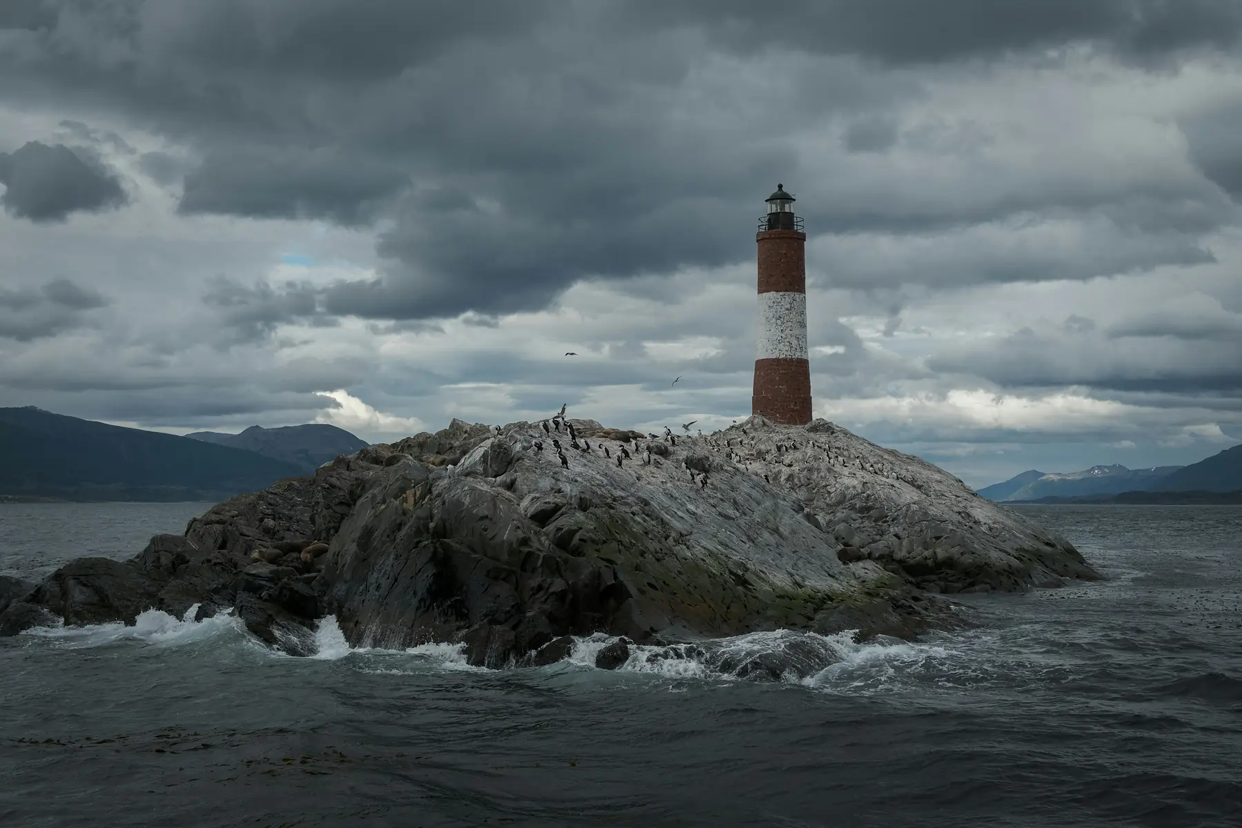 The red-and-white Les Eclaireurs Lighthouse on a rocky island in the Beagle Channel
